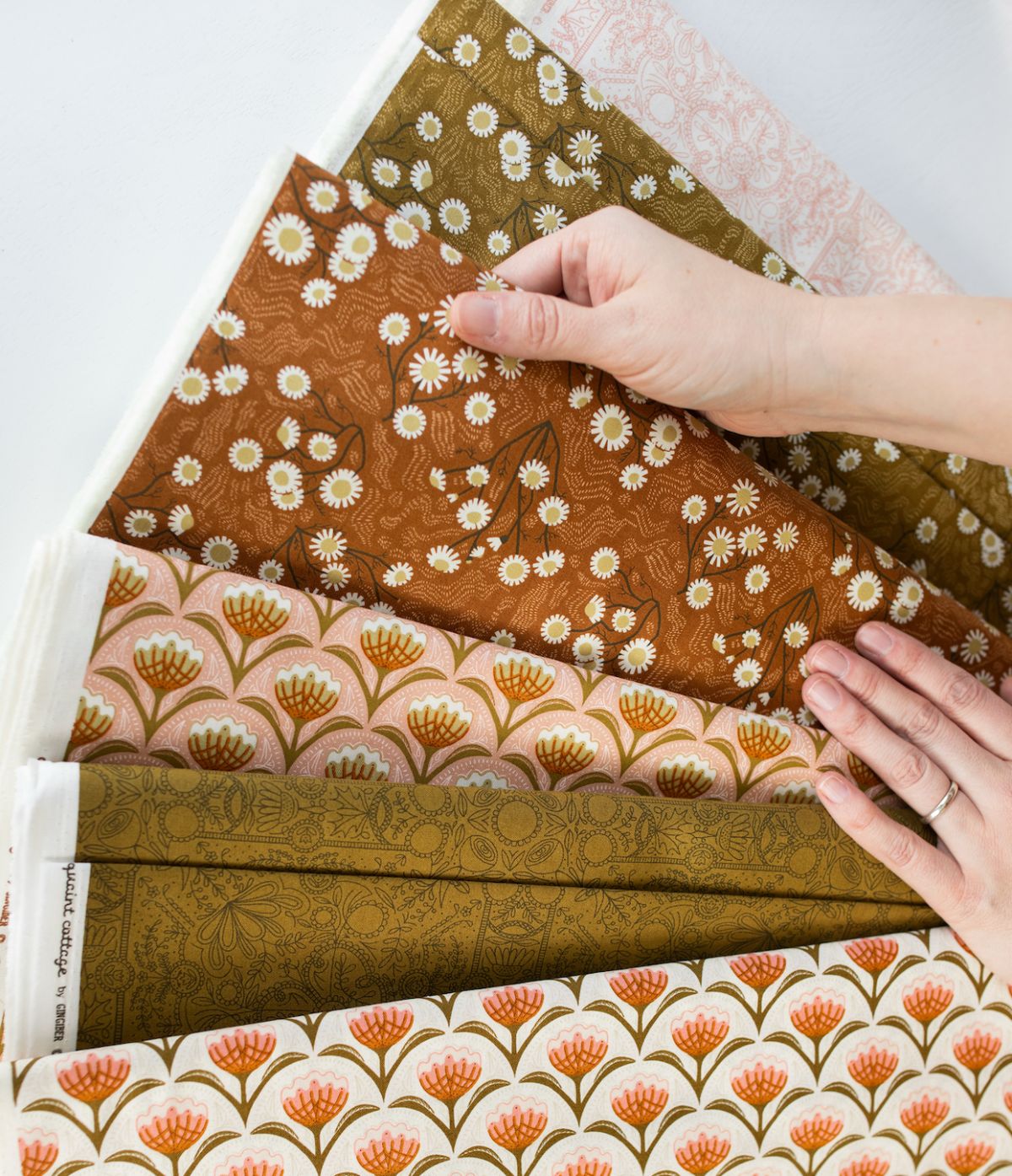 Hands fanning out Stacie's printed fabric designs