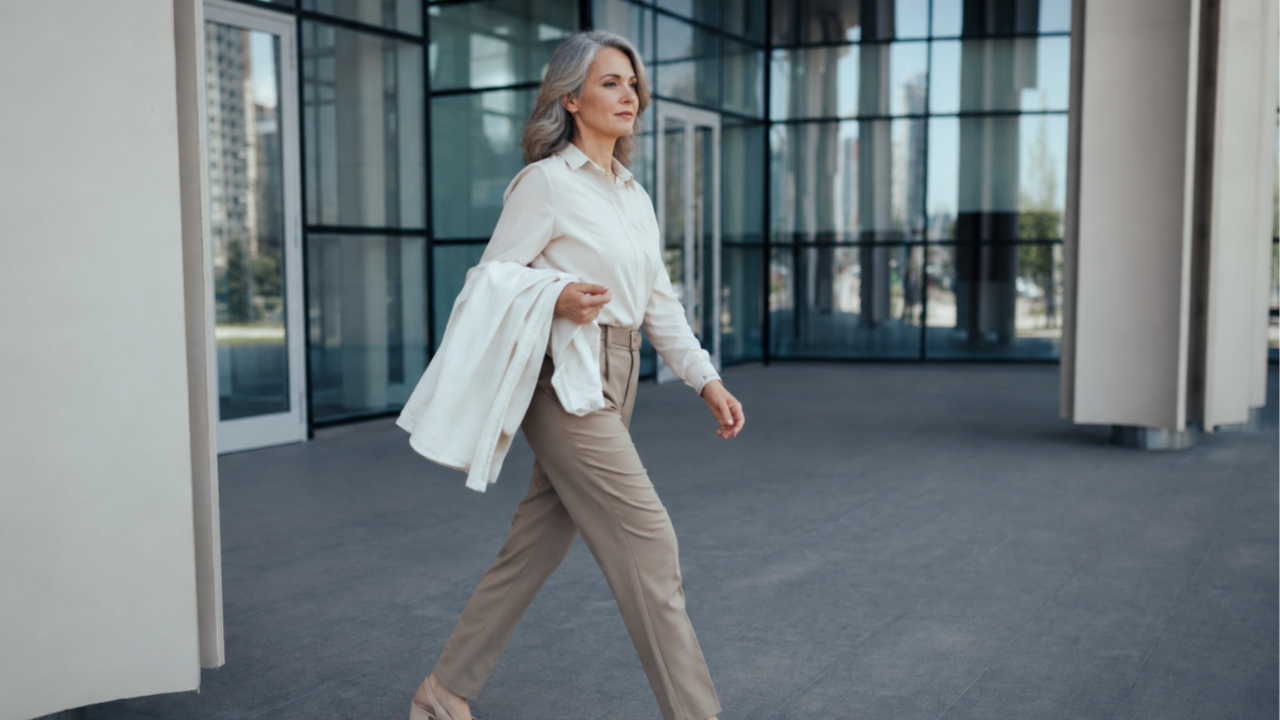 Confident woman in her 50s walking away from a modern corporate office building