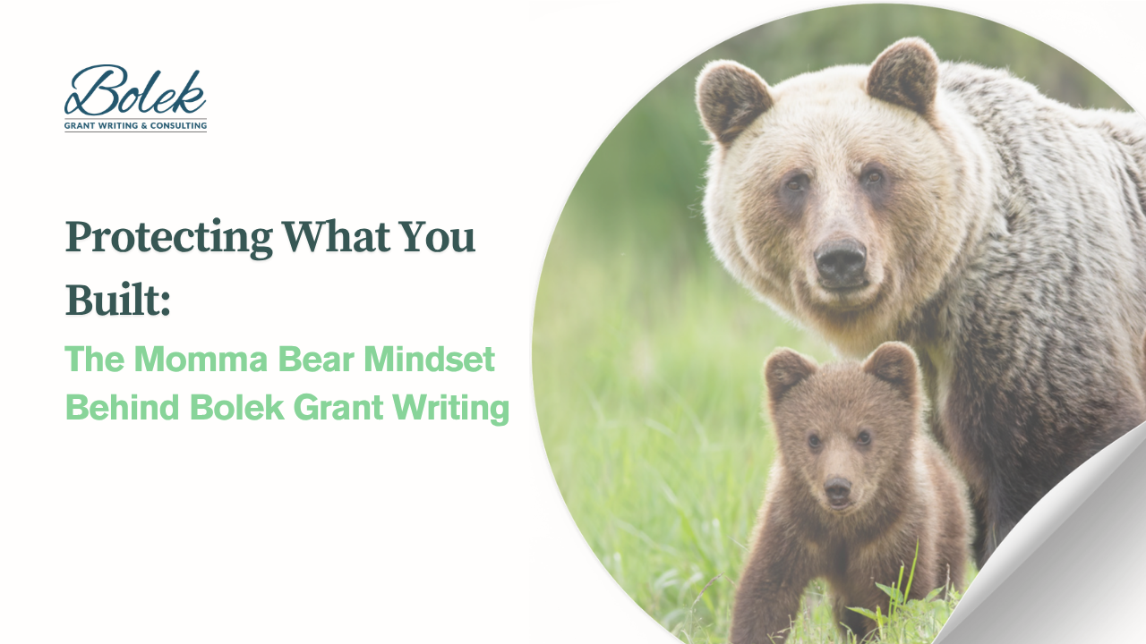 A mama bear and her cub standing together in a green field, illustrating the momma bear mindset of protection and leadership in business.
