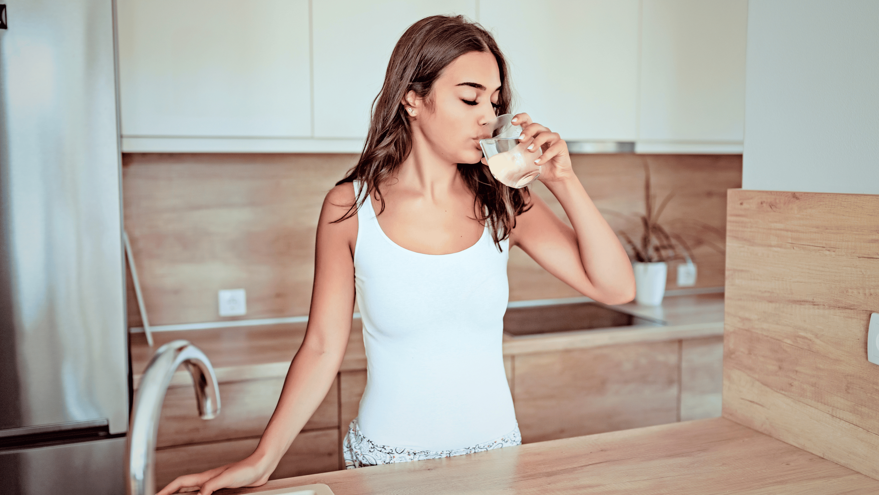 A woman with clear skin and a glass of water — representing the skin benefits of cutting back on alcohol