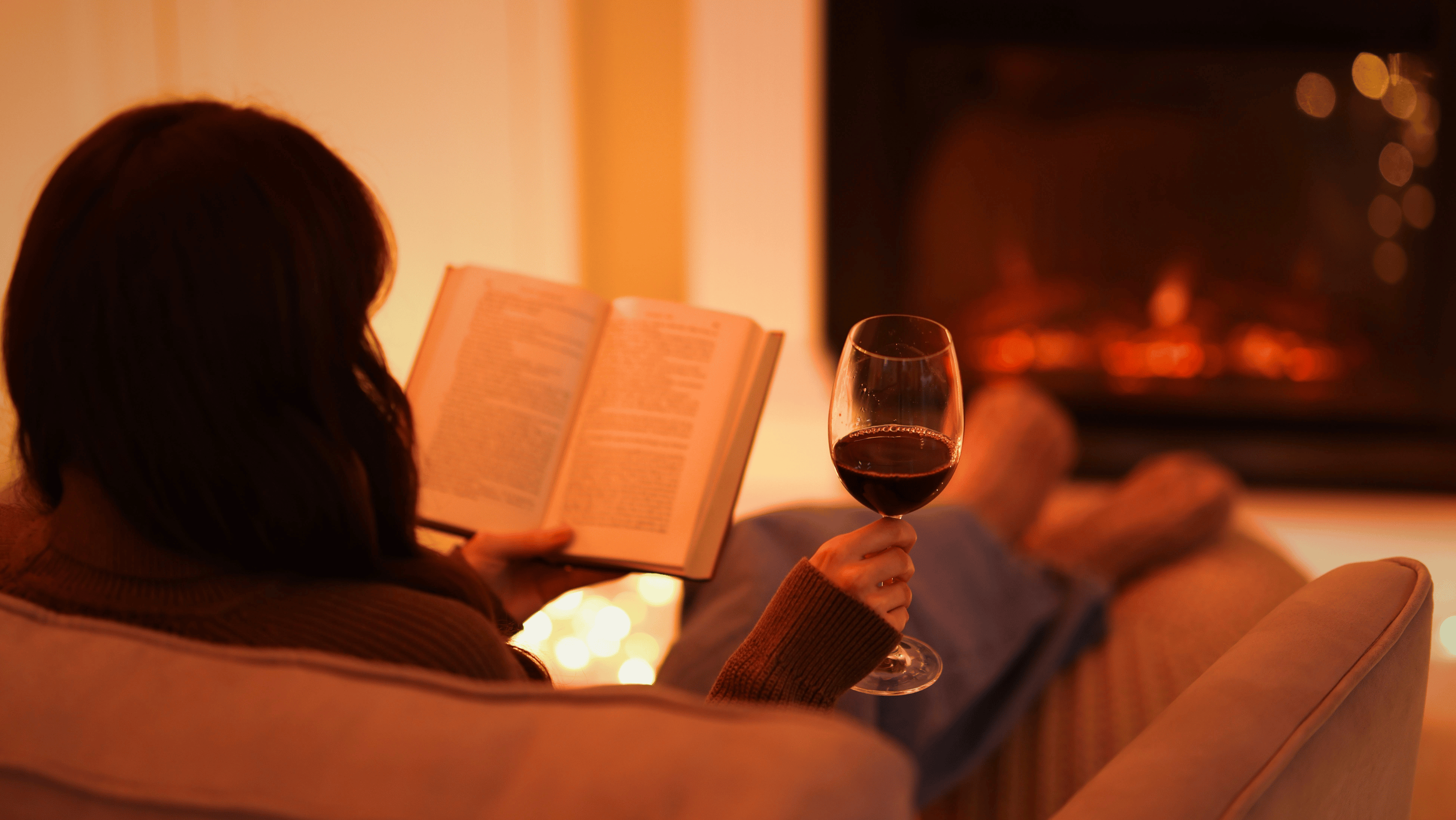 A woman sitting quietly in the evening with a glass of wine, looking thoughtful