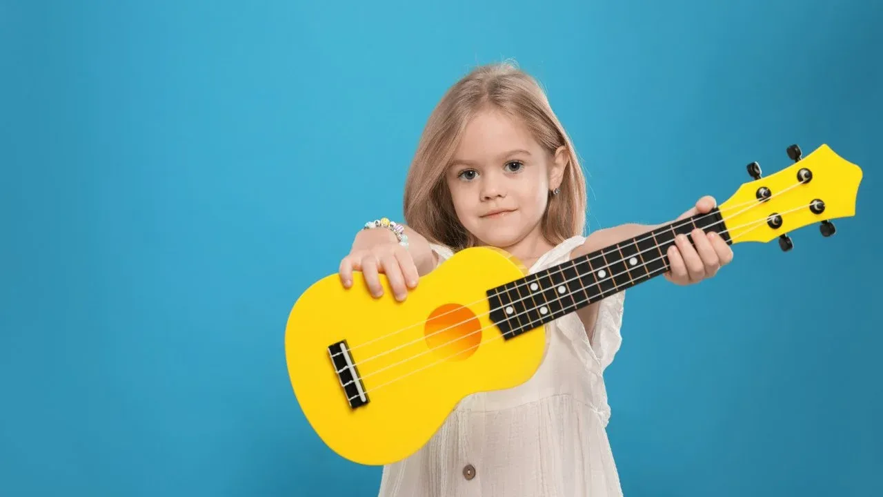 Young girl holding a yellow ukulele, representing online ukulele lessons for homeschool kids funded by ESA