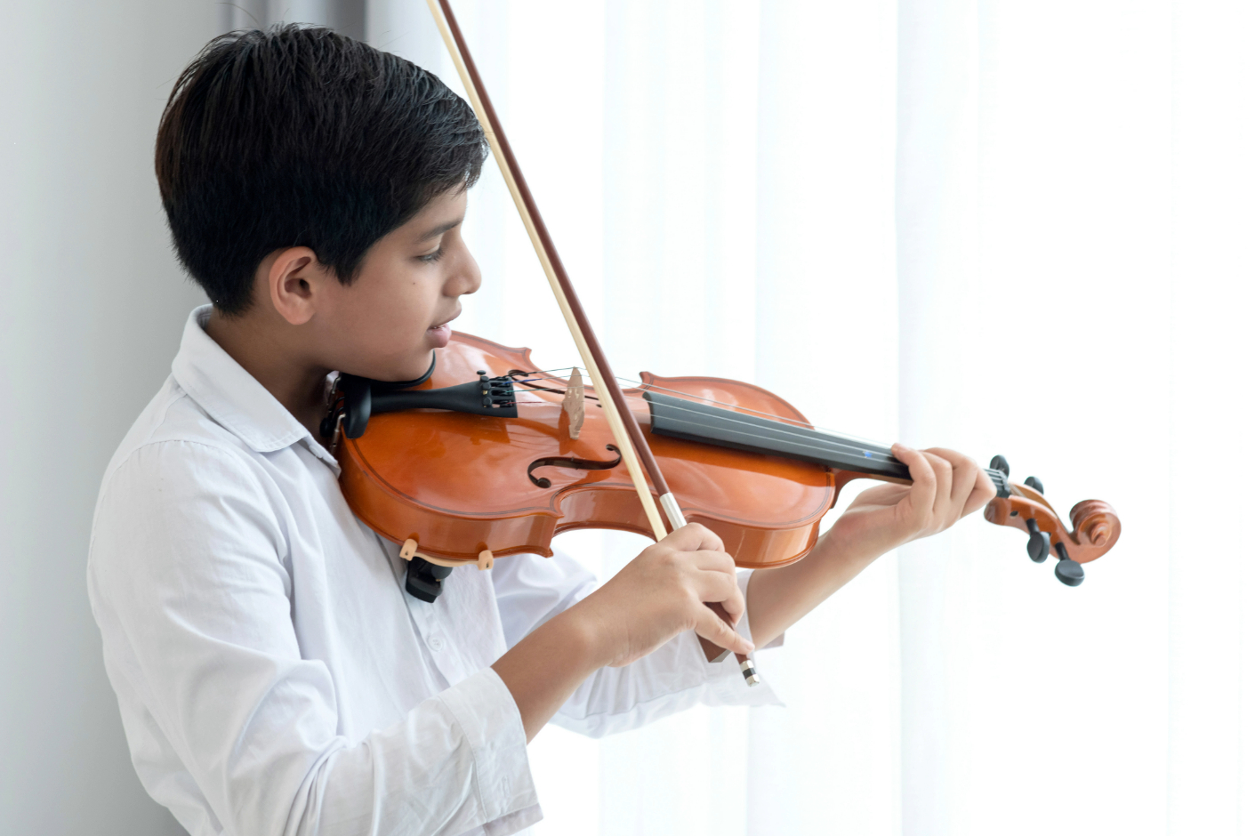 A violinist performing in dramatic stage lighting against a dark background