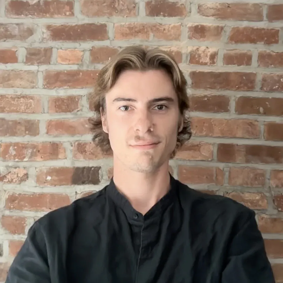 Tyler, a Maestro Music piano teacher, smiling in front of a brick wall