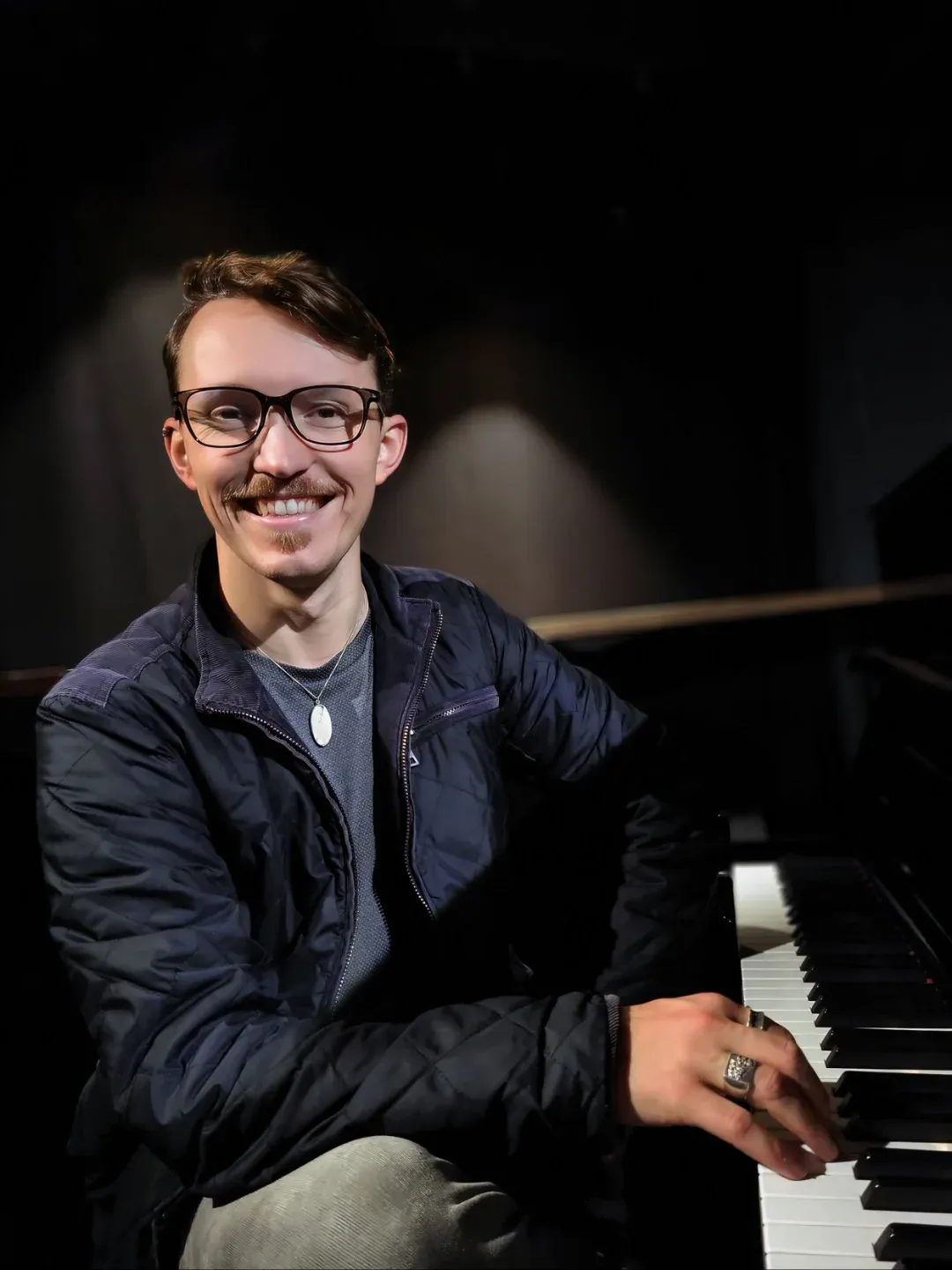 Chase Chandler, online voice, piano, and trumpet teacher at Maestro Music, seated at a grand piano