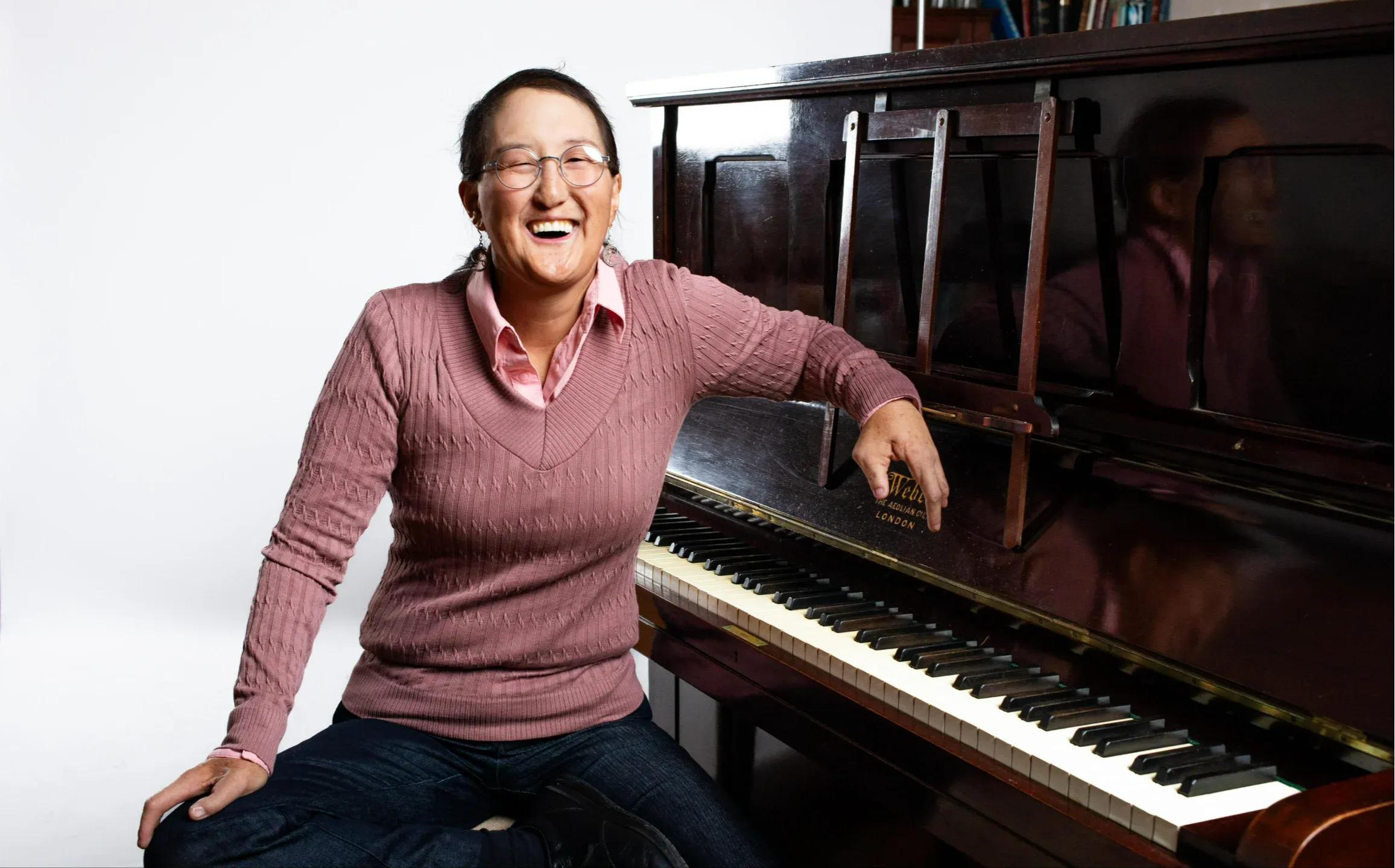 Camille Hatton, online piano, voice, and percussion teacher at Maestro Music, seated beside an upright piano