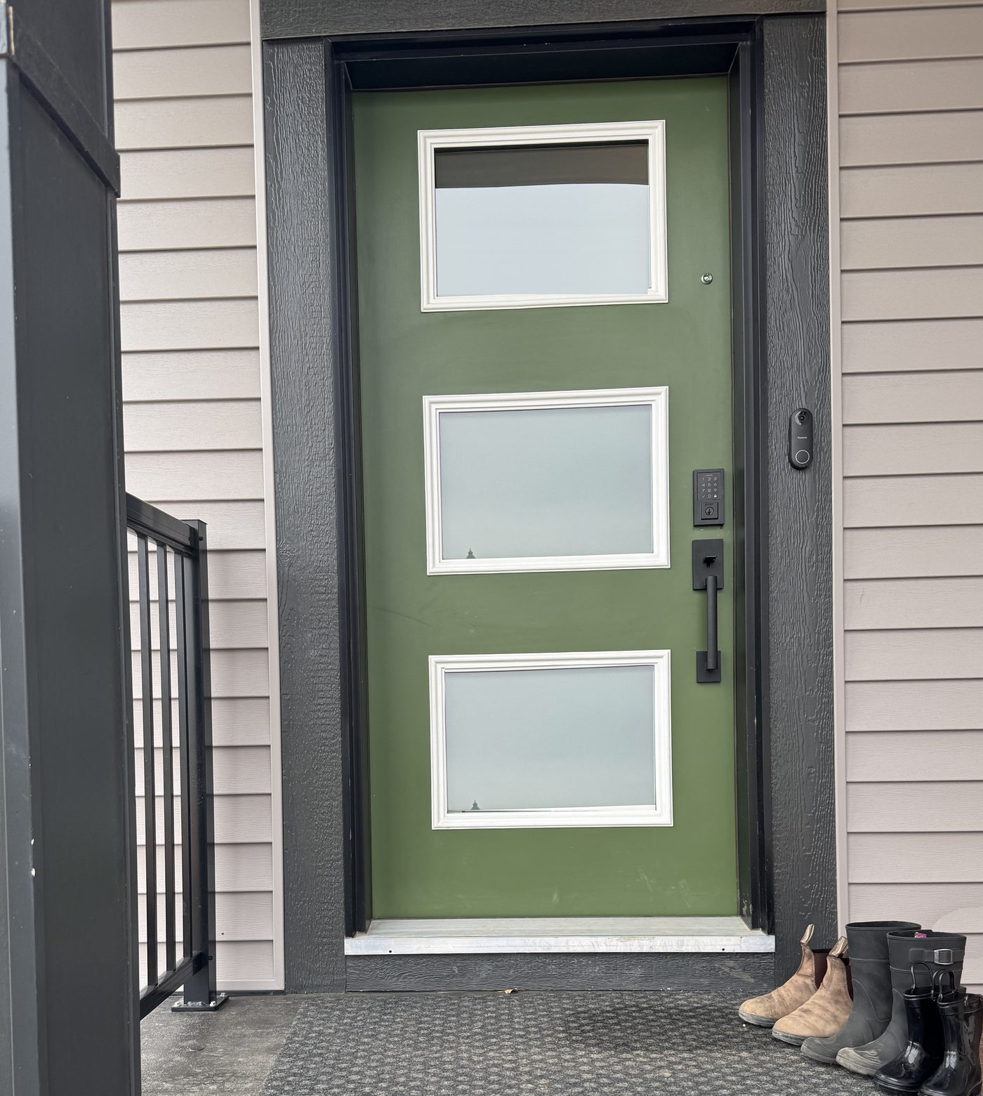 Kayla's real front porch: a forest green door with three frosted windows and boots lined up on the mat