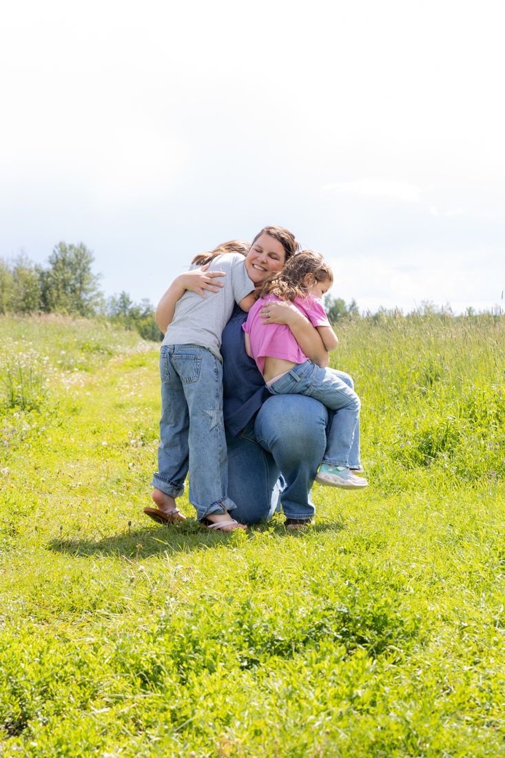 Kayla kneeling in a grassy field, wrapped in a big group hug