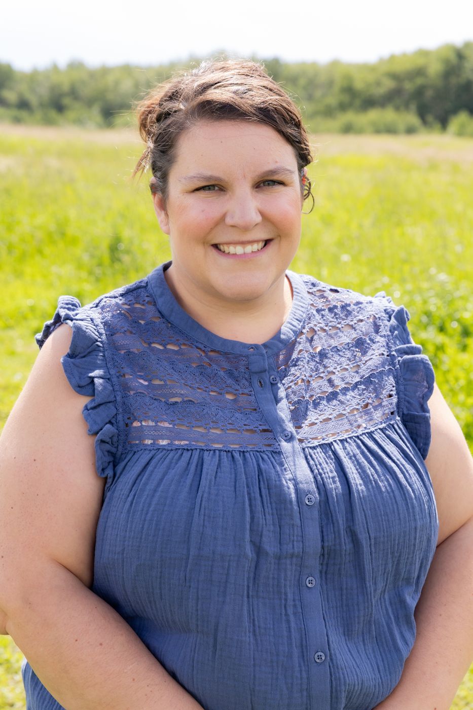 Kayla smiling in a sunny field, wearing a blue top