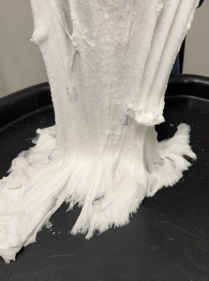 Thick white spiderweb slime stretched up from a black sensory tray