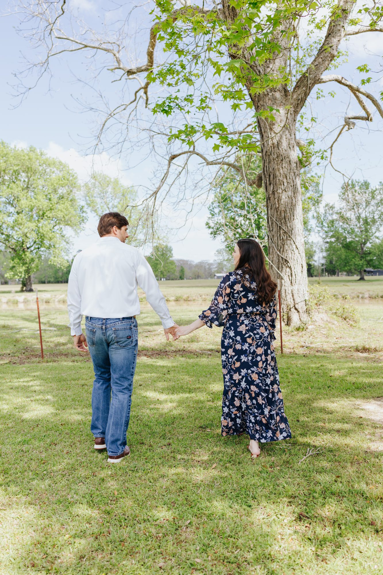 Chase and Katie walking hand in hand under a tree