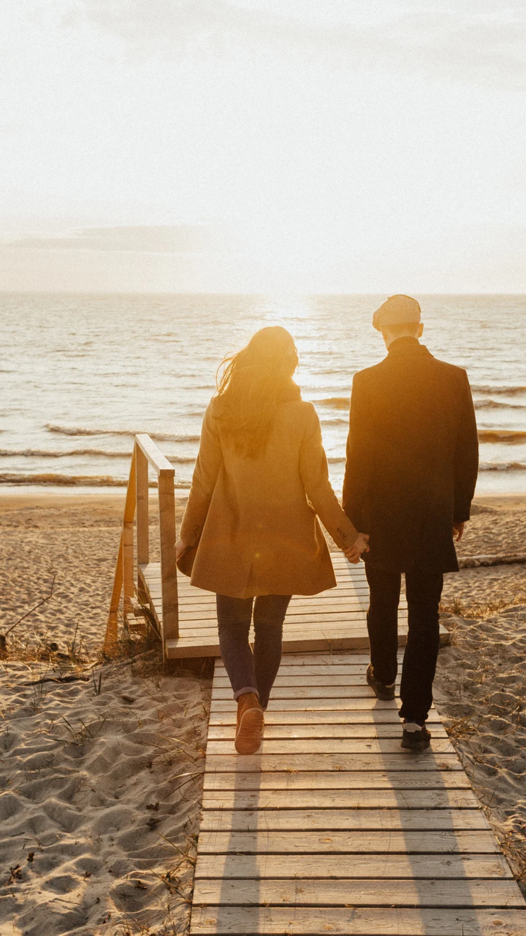 A couple walking hand in hand toward the beach