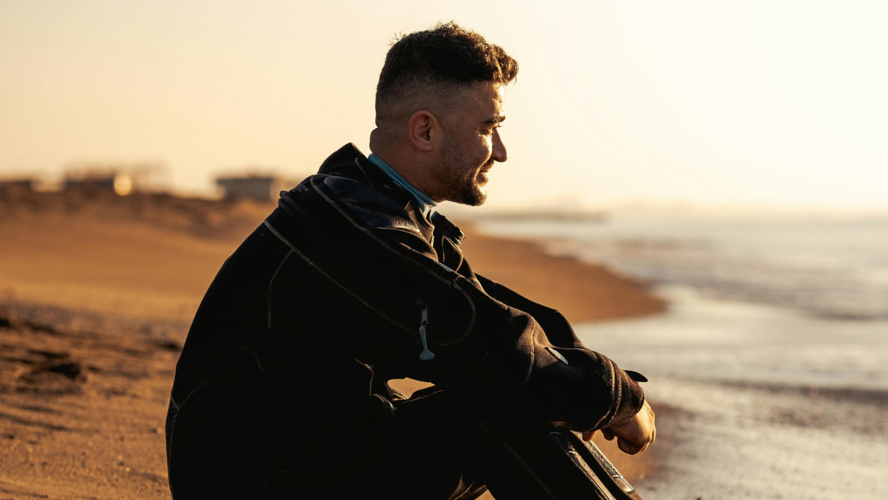 A man sitting on the beach at sunset