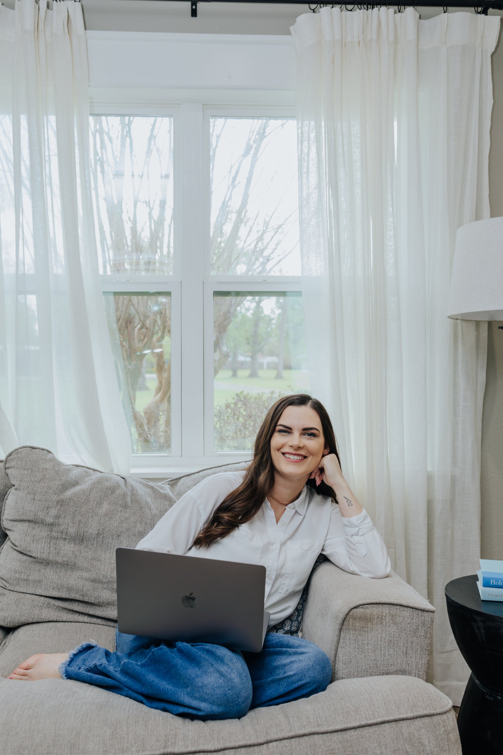 Kathryn Fayle smiling on her couch with a laptop