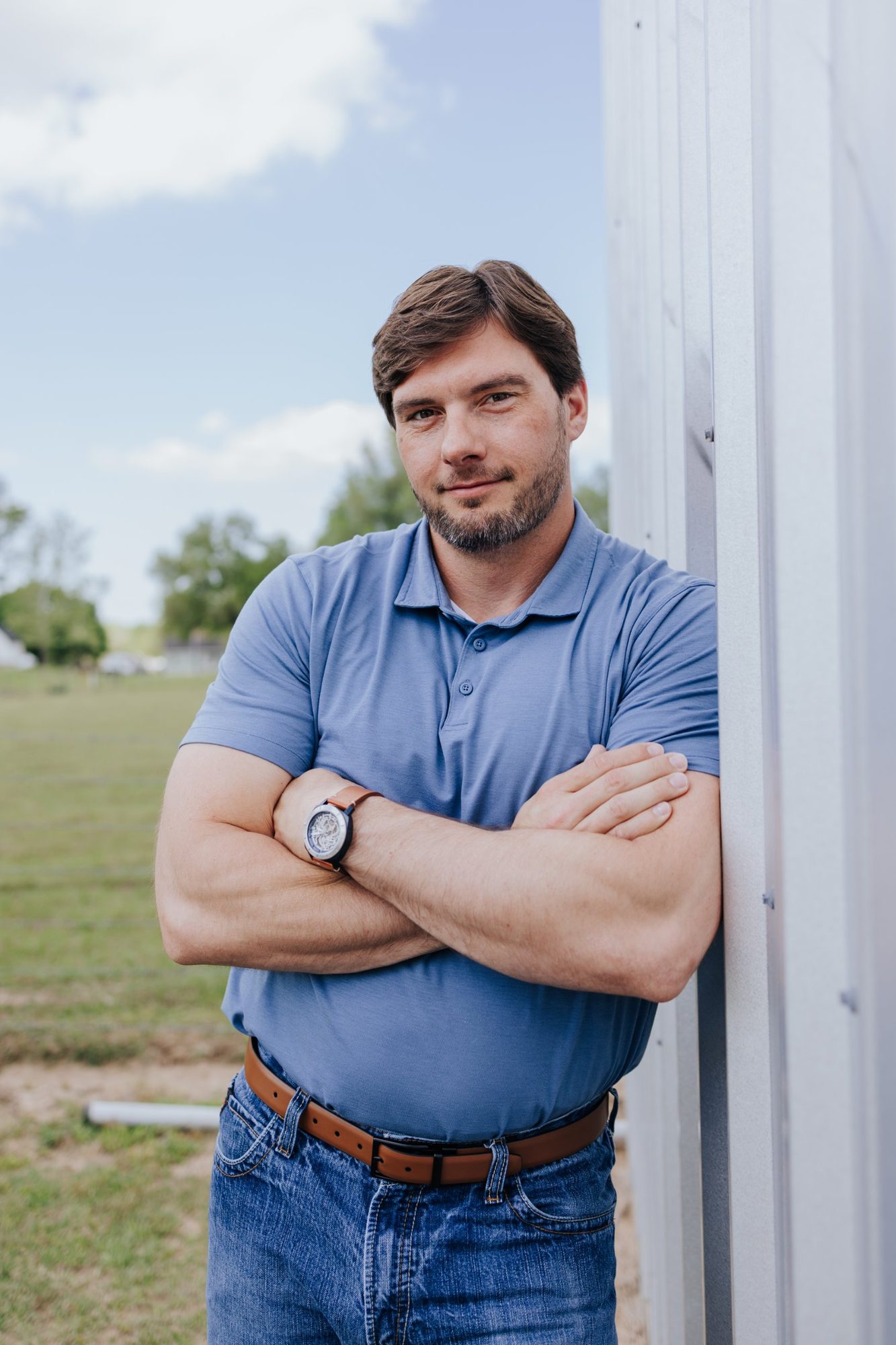 Chase Fayle leaning against a building outdoors with his arms crossed