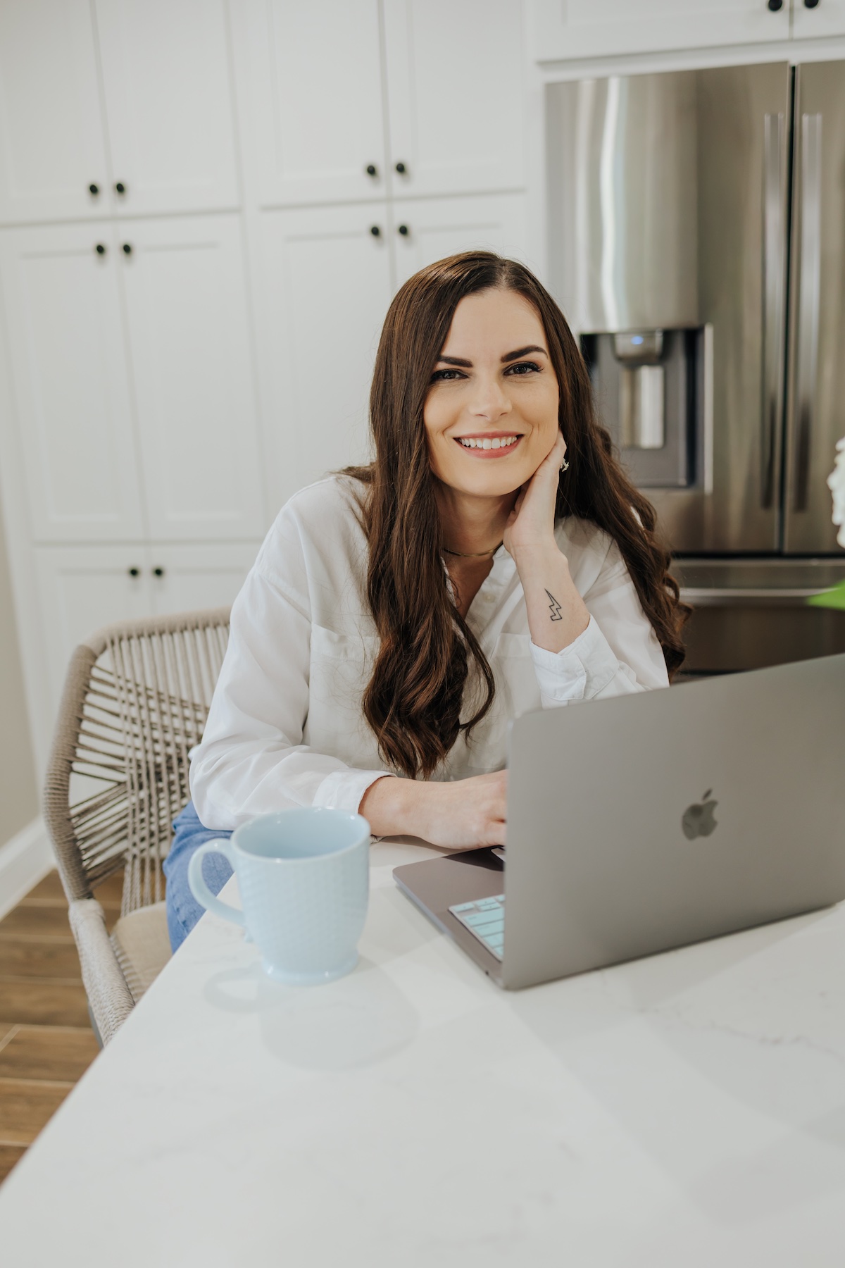Katie Fayle smiling at her laptop in her kitchen