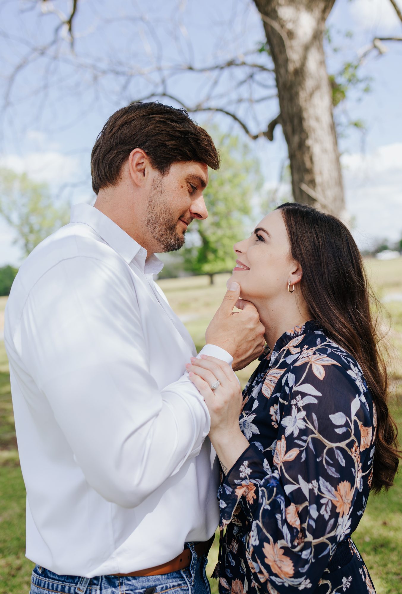 Chase gently lifting Katie’s chin as they smile at each other outdoors