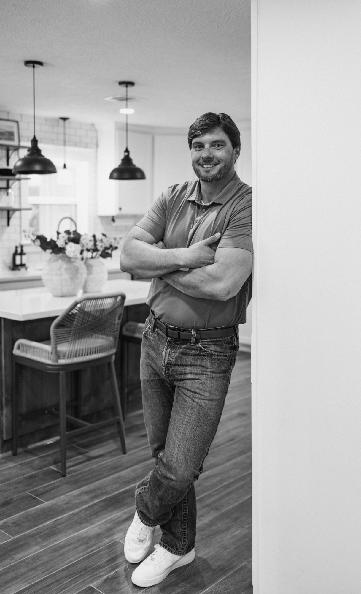 Black and white photo of Chase leaning in a doorway by the kitchen