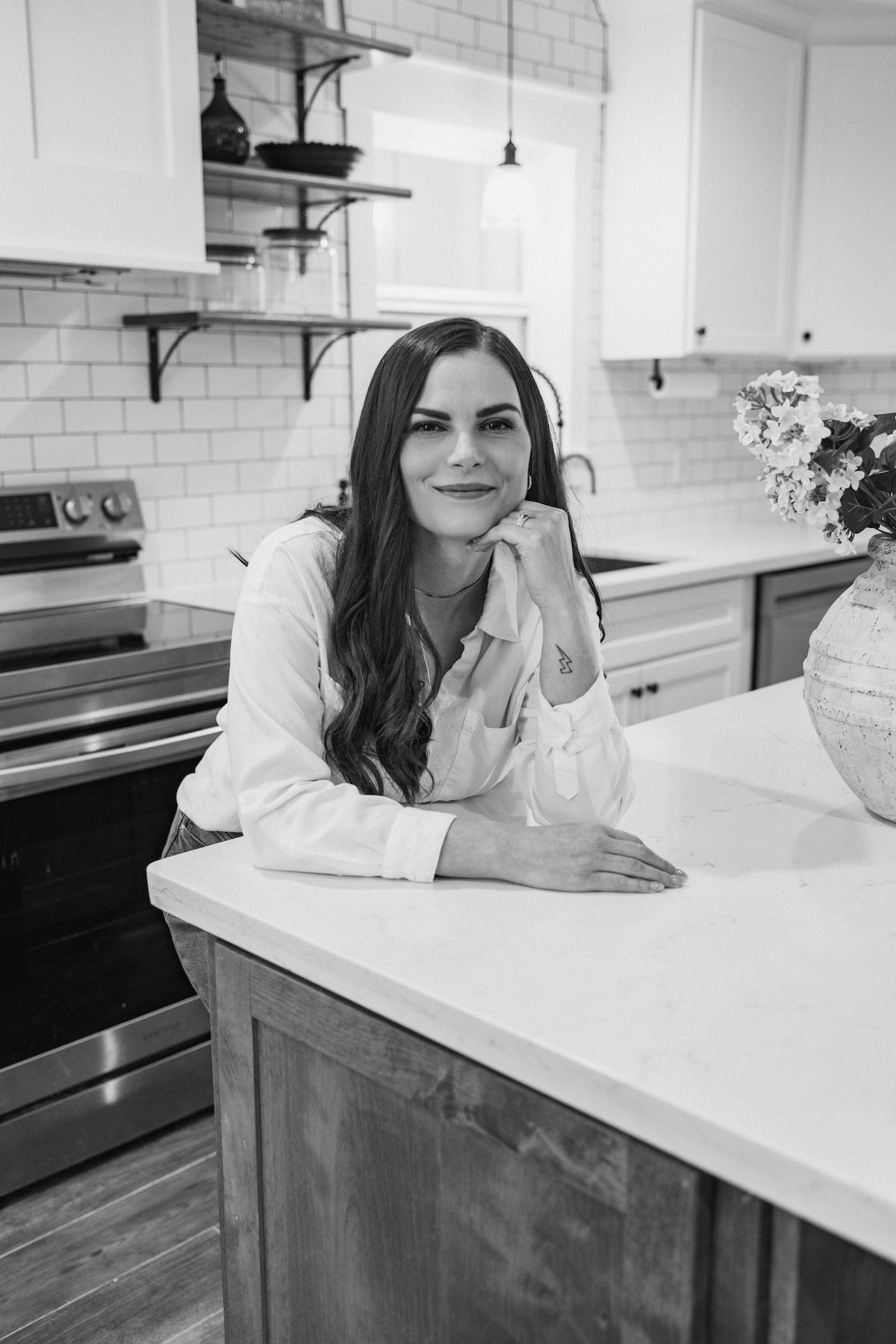 Black and white photo of Katie leaning on her kitchen counter