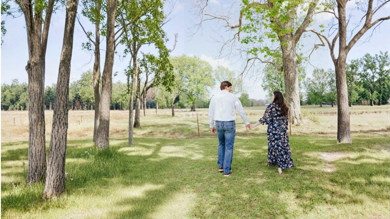 Katie and Chase Fayle walking hand in hand through a field