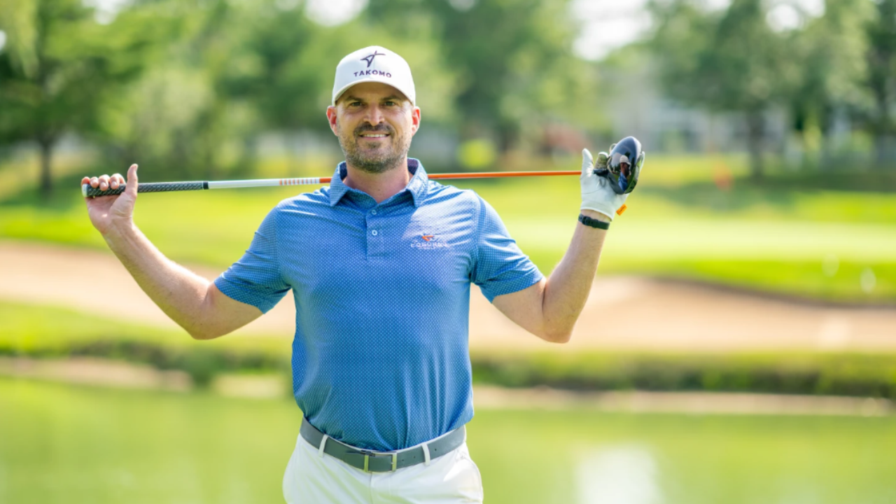 Golf instructor Eric Cogorno smiling at the camera while holding a golf club