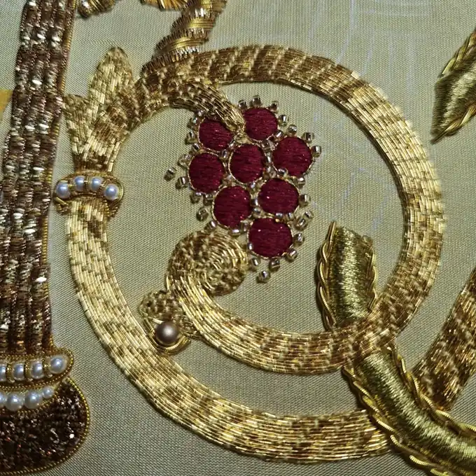 Macro detail of goldwork braid with ruby-red beads and pearls
