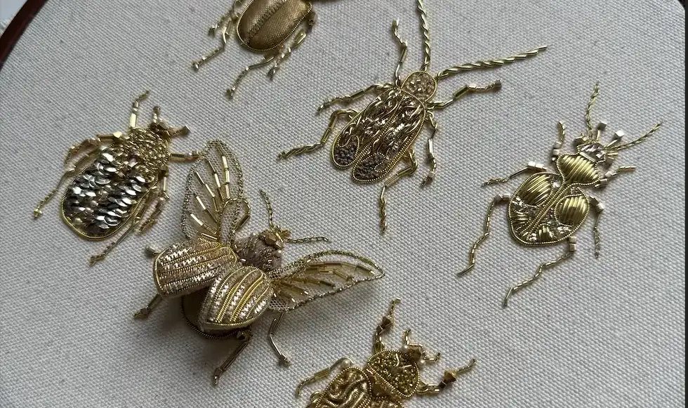 Six golden insects embroidered in metal thread on linen