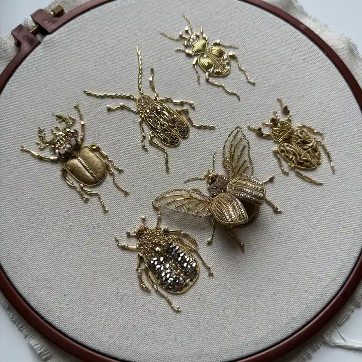 Six golden bug brooches arranged in an embroidery hoop, Golden Bugs goldwork course