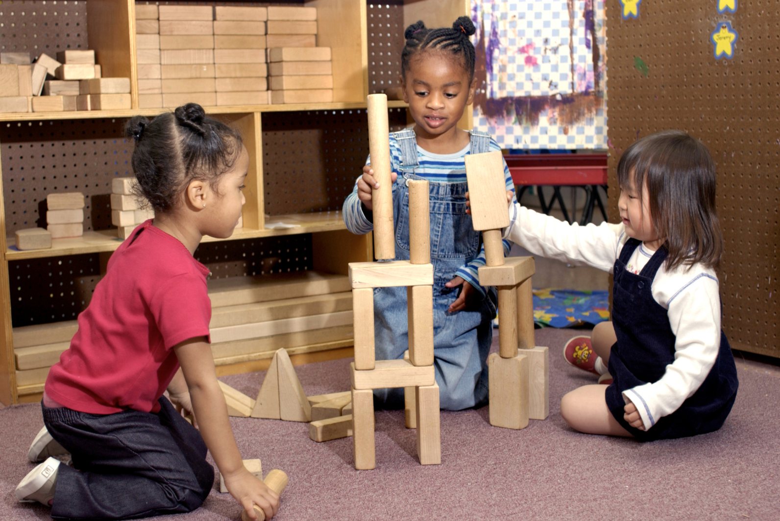 Three children building a tower of blocks together
