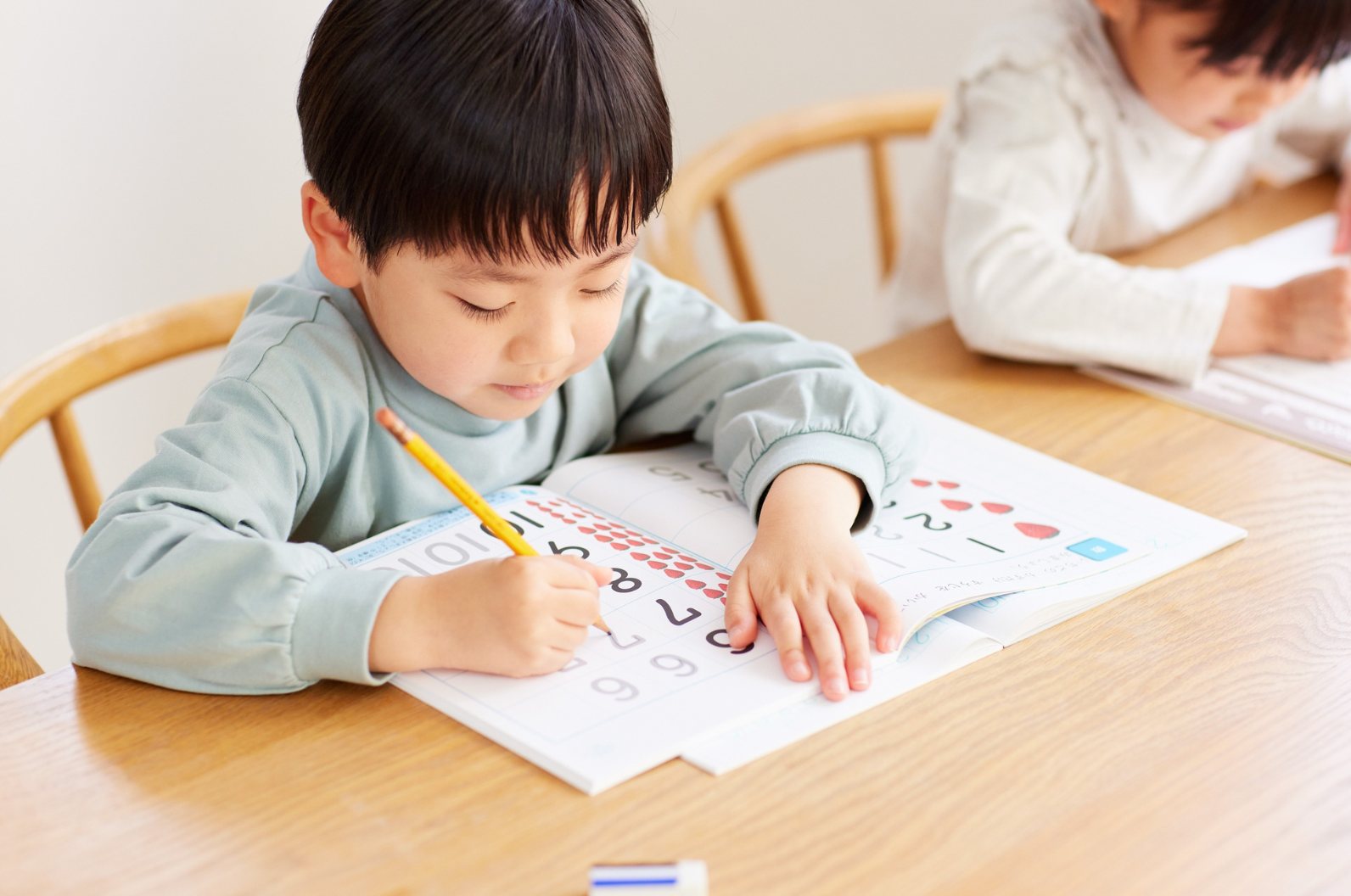 A child practising writing numbers at a table