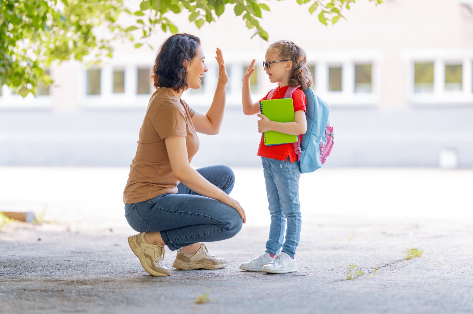 A parent and child sharing a high five outside school