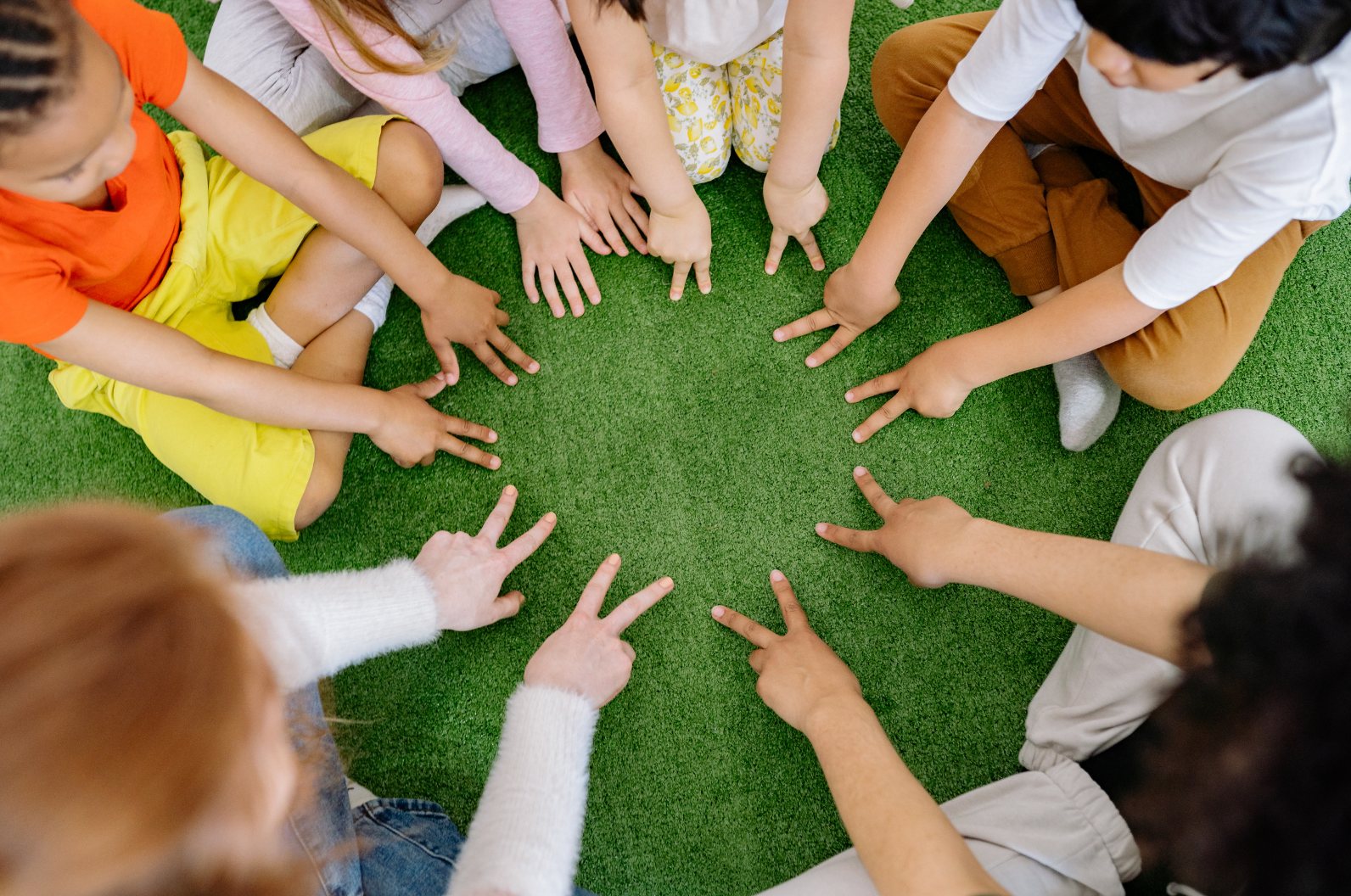 Children sitting in a circle, hands touching in the middle