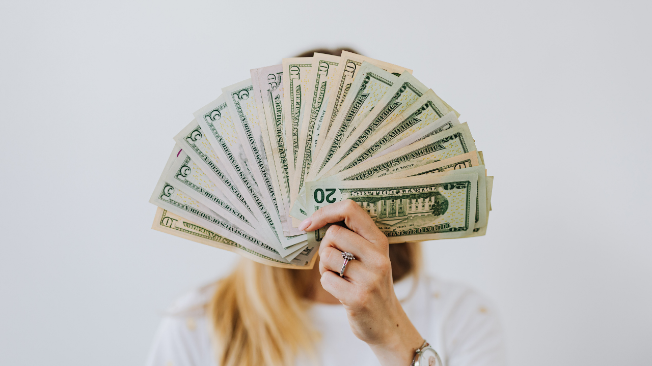 Nurse practitioner holding stacks of cash representing profitable healthcare specialties and practice revenue growth.