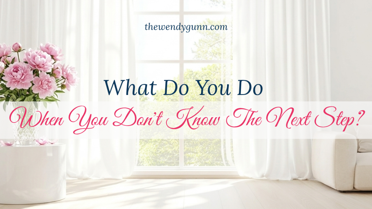 Inspirational graphic featuring a bright room with white curtains and sunlight streaming through a large window, with pink peonies in a vase on the left. The text reads: "What Do You Do When You Don't Know The Next Step?"