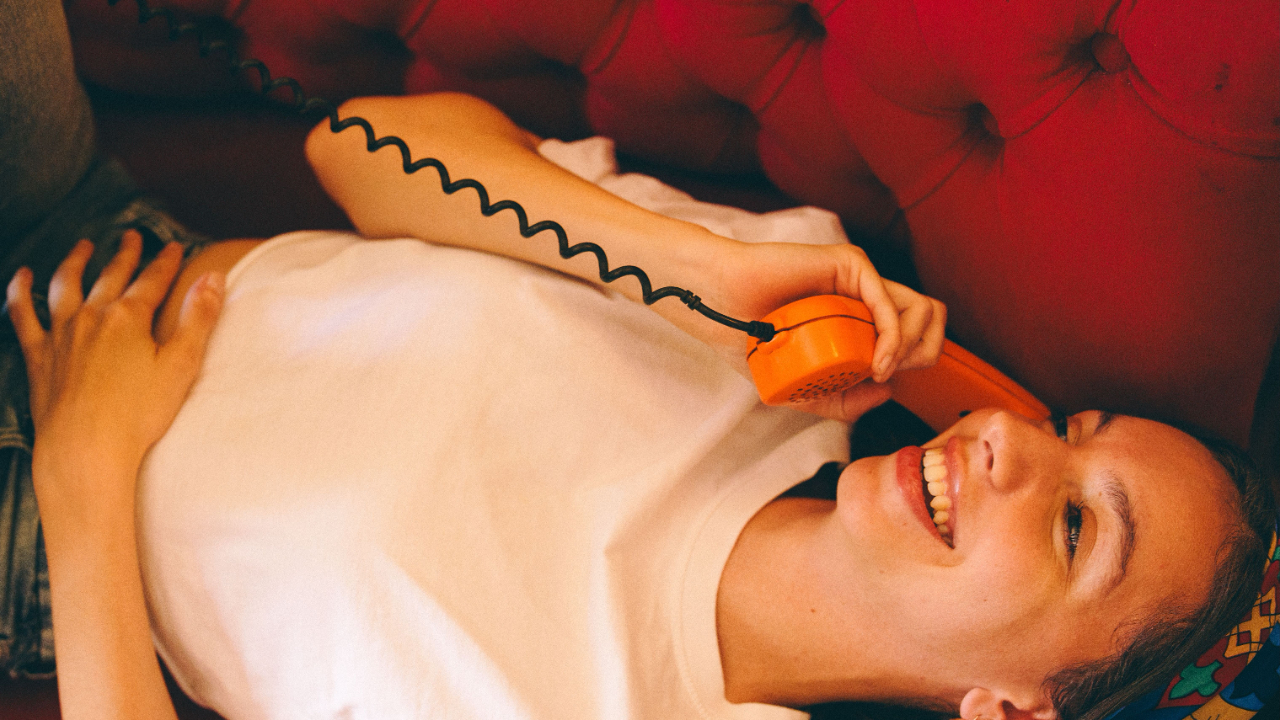 femme qui regarde son téléphone en souriant, début de relation, je m'attache trop vite