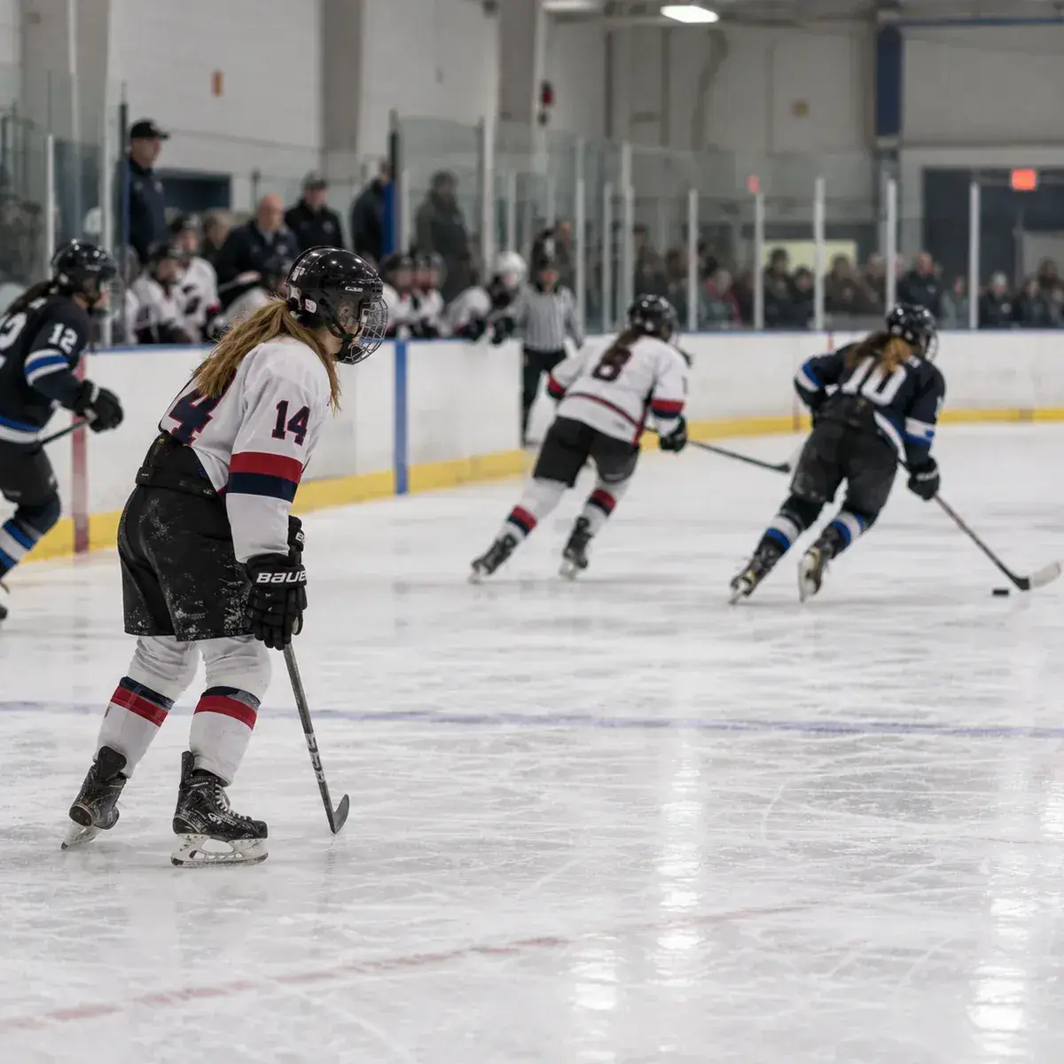 Youth ice hockey player standing still on the ice while play moves away from her