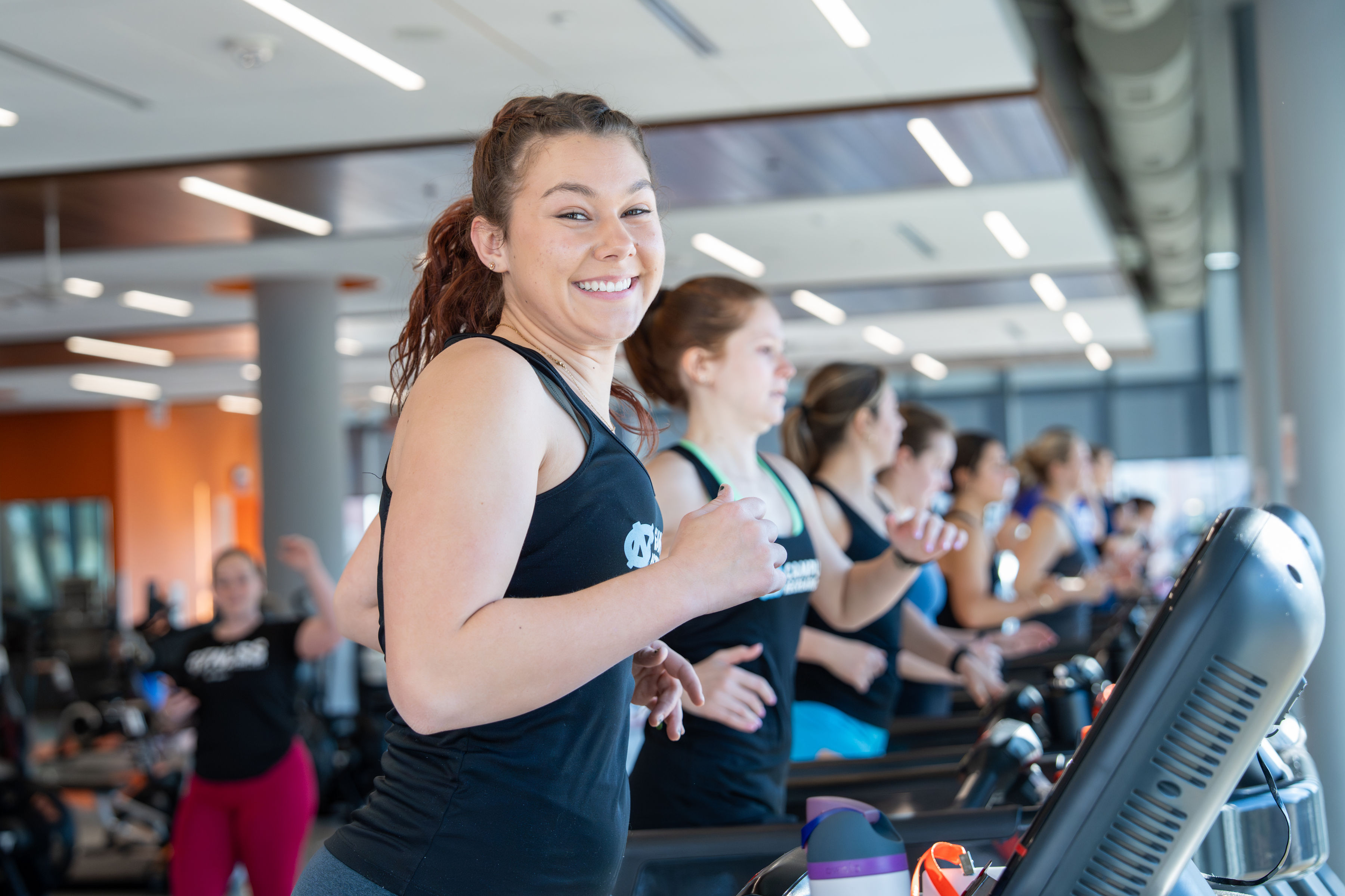 Smiling student training alongside classmates on the fitness floor