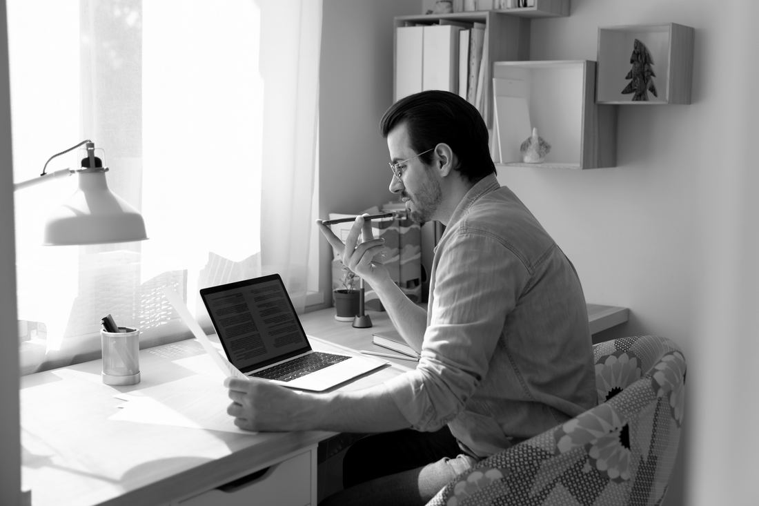 An assistant reviewing paperwork at a desk beside an open laptop