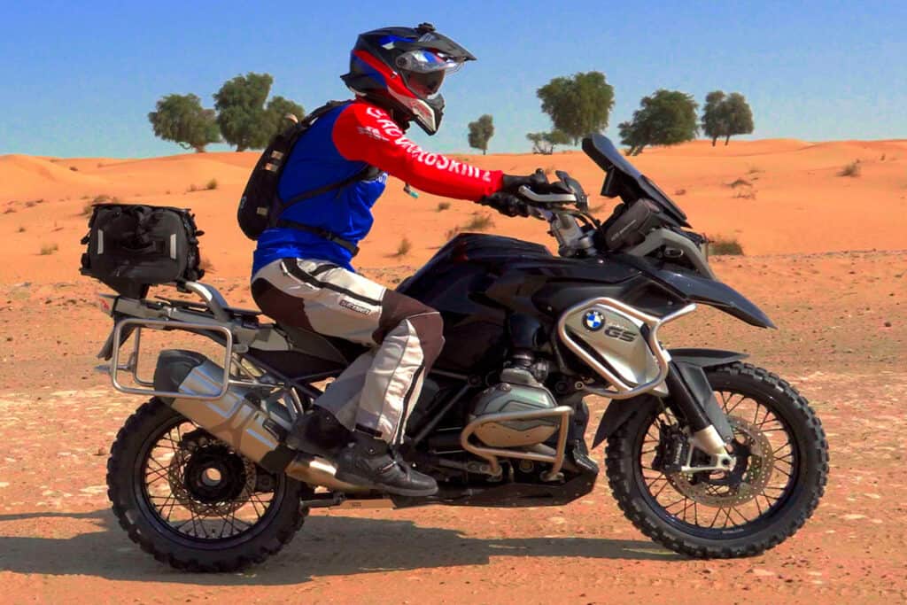 Rider performing a side saddle mount on an ADV motorcycle