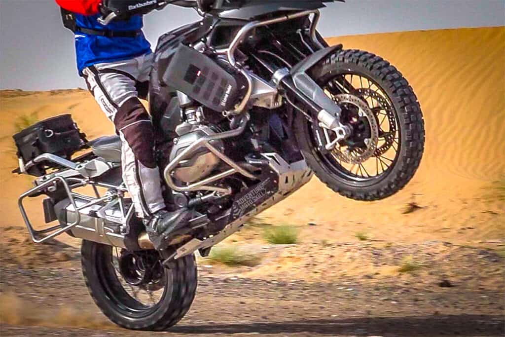 ADV motorcycle lifting its front wheel with the rider’s feet in mid-arch position