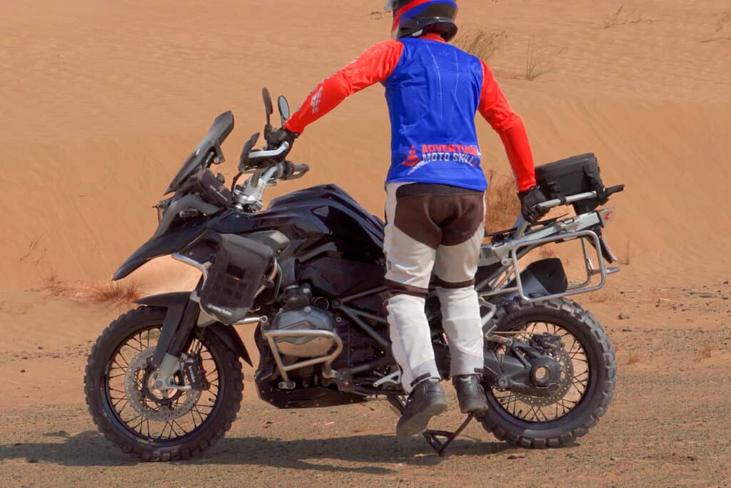 BMW R1200GS being put on its center stand on hard-pack gravel