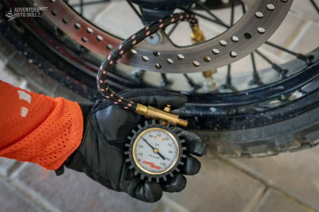 Checking motorcycle tire pressure with an analog dial gauge