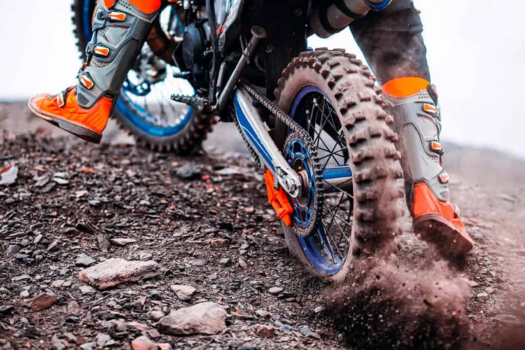 Knobby dual-sport motorcycle tire digging into gravel on off-road terrain