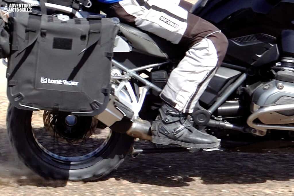 Close-up of a seated rider’s right foot on the peg while riding on gravel