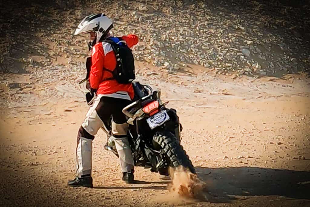Rider standing beside a BMW R1200GS about to perform an elephant turn