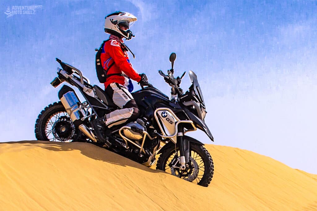 Motorcycle rider sitting on a BMW R1200GS motorcycle on a sand dune
