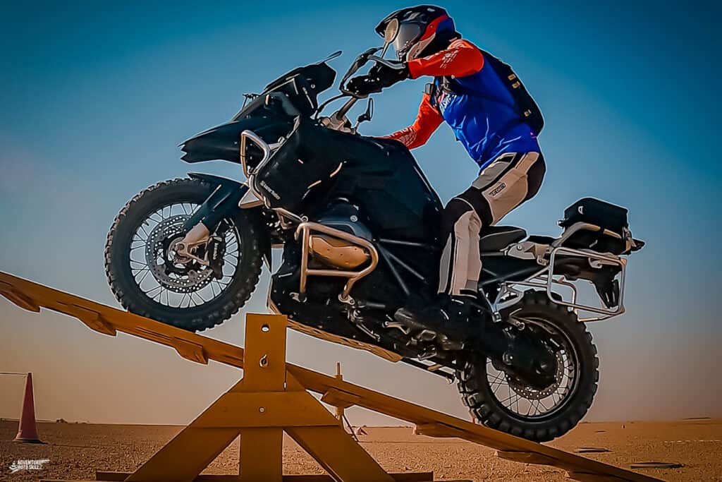Motorcycle rider riding over a teeter-totter obstacle