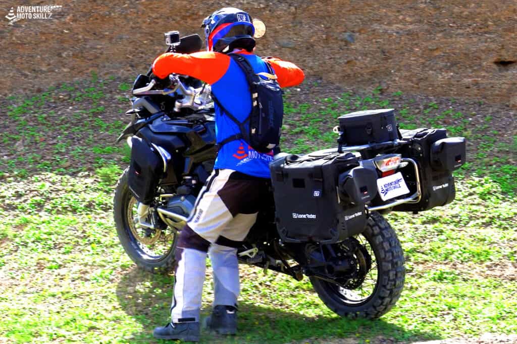 Adventure motorcycle rider standing on the left side of the bike while walking it