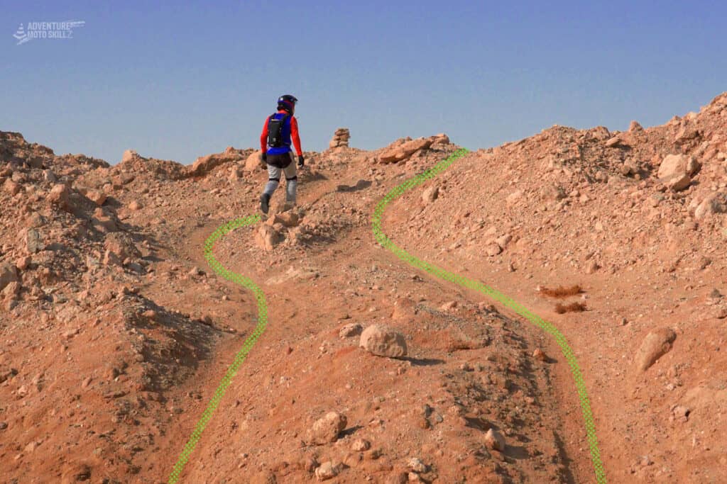 Walking an unfamiliar off-road trail section before riding it on a motorcycle
