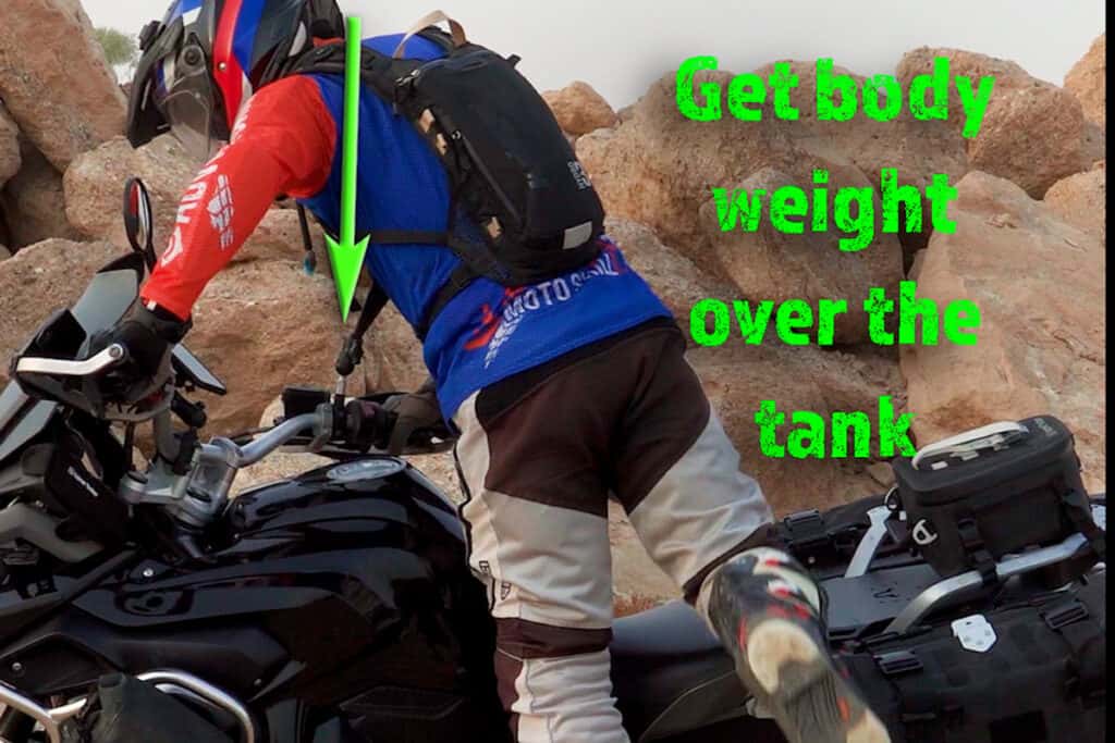 Rider shifting body weight over the center line while mounting an ADV motorcycle